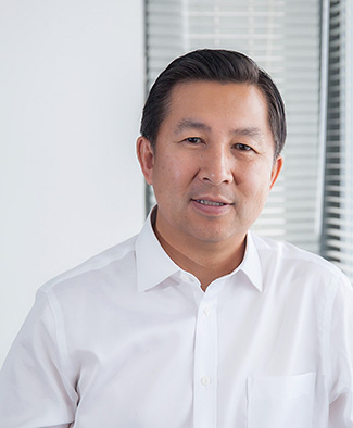 Jie Zhang near a window with blinds 