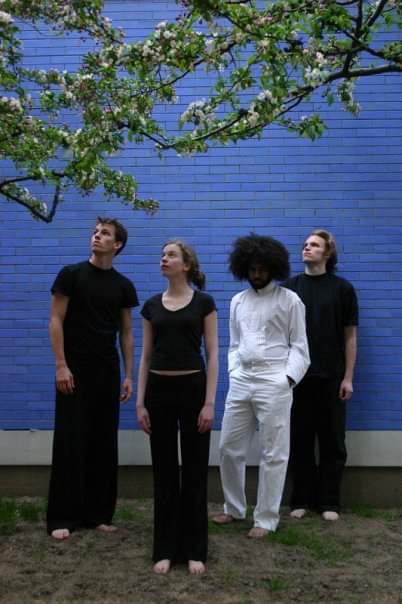 Four people in front of a blue brick wall