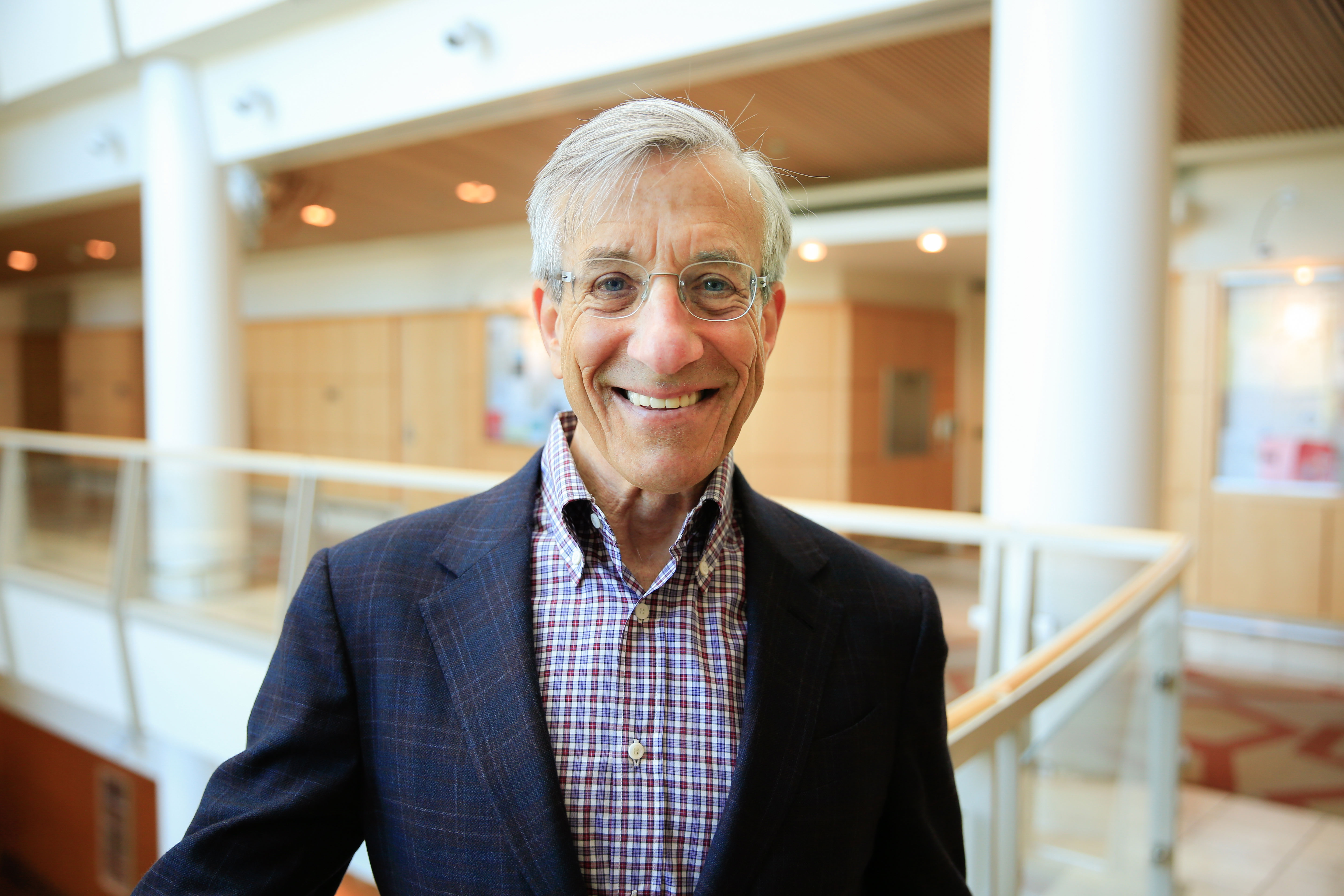 Michael Lesh stands in a large lobby at the top of a staircase.