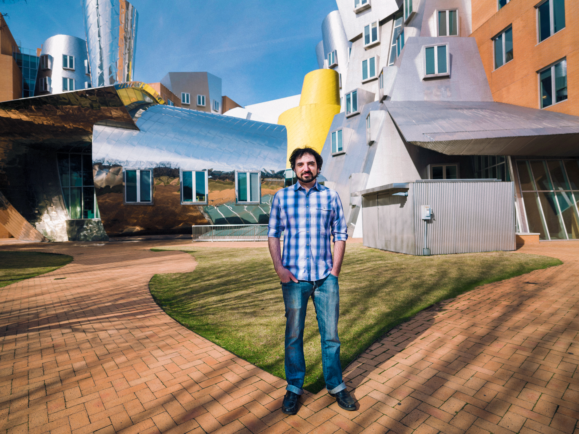 MIT alum Greg Falco standing in a courtyard outside in front of the MIT Stata Center