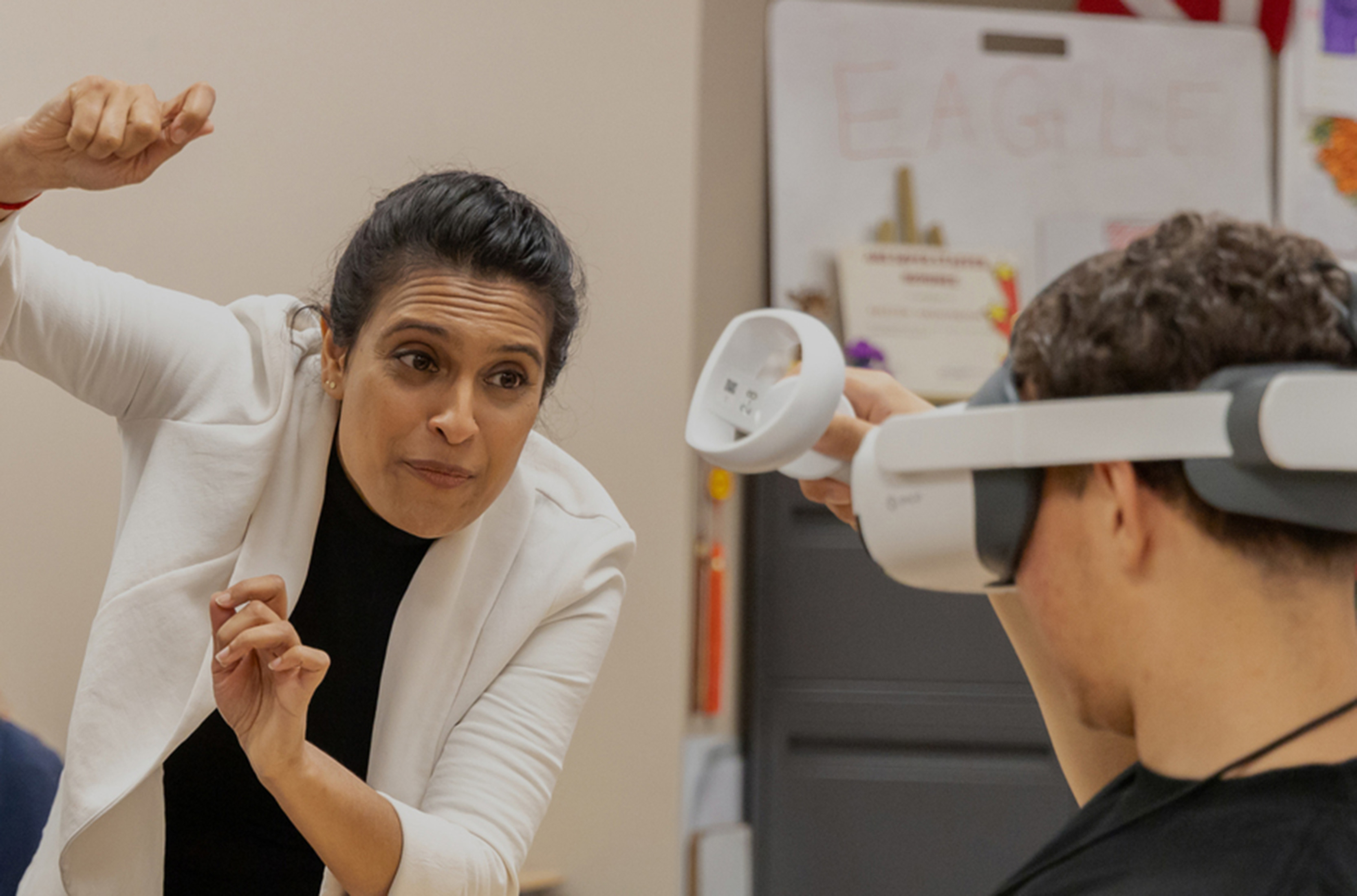 Anurupa Ganguly gestures while helping a student wearing VR goggles.