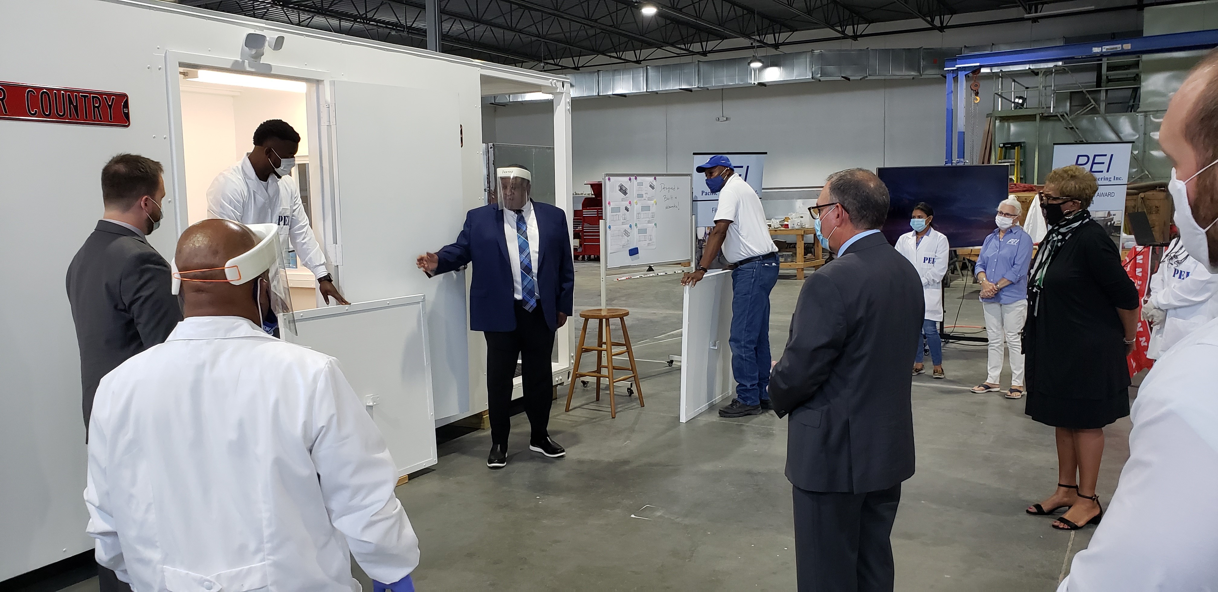 A group of people watches the demonstration of a Covid testing unit