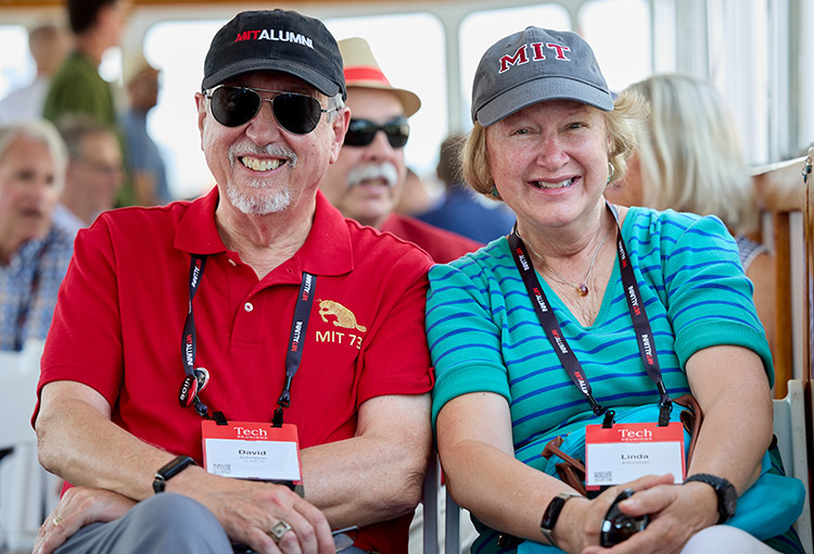 A man and woman pose in MIT hats and other gear.