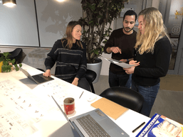 three people working at a desk 