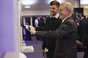 Two men in suits looking at an object 